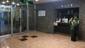 A reception area with a 'FRONT' sign, a map, and a reception desk with a plant. - Pension Benkei (Hachinohe)