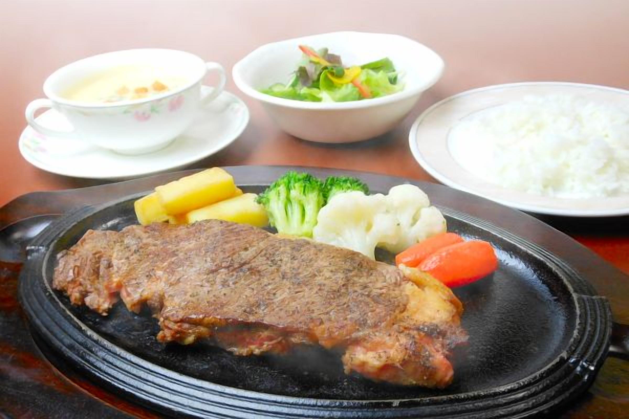 A plate with a steak, vegetables, and rice.