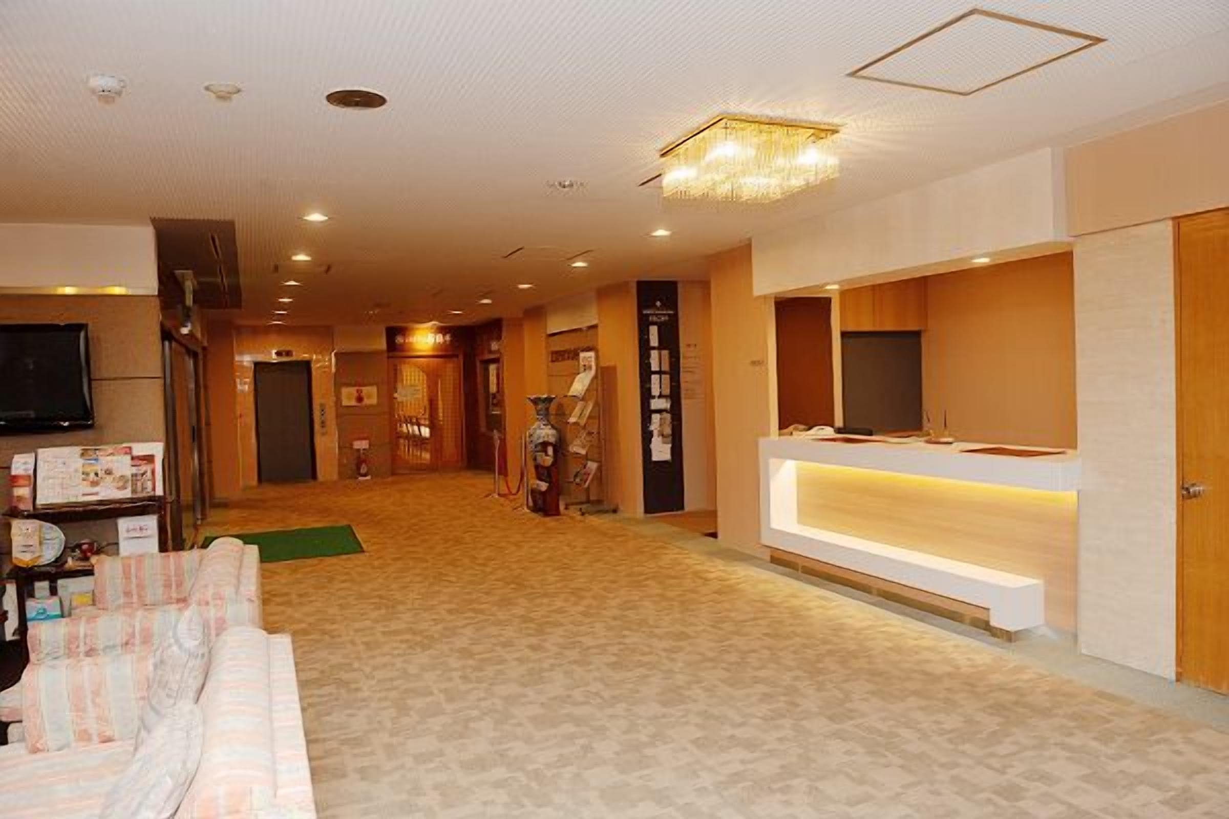 A hotel lobby with a reception desk, a television, and a seating area.