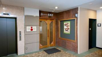 An elevator with a digital display, a wooden door, and a wall-mounted sign.