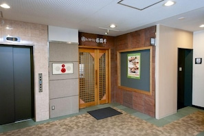 An elevator with a digital display, a wooden door, and a wall-mounted sign.