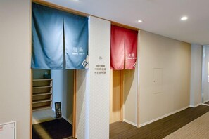 A hotel corridor with a staircase, a men's and women's bathroom, and a door.