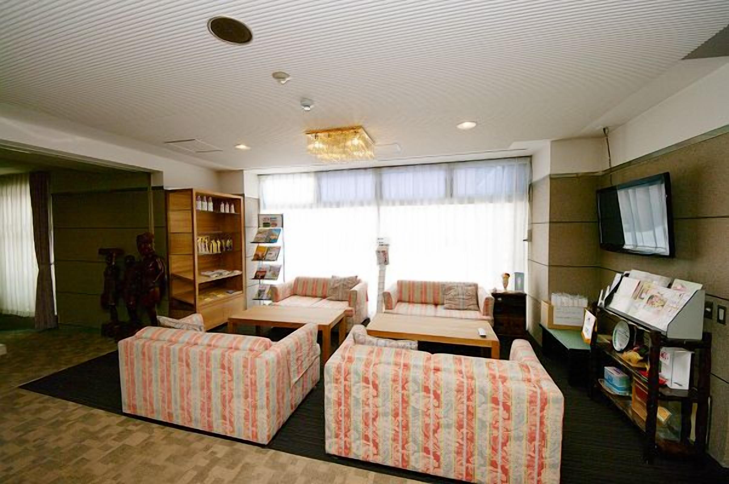 A hotel room with a sofa set, a television, and a bookshelf.