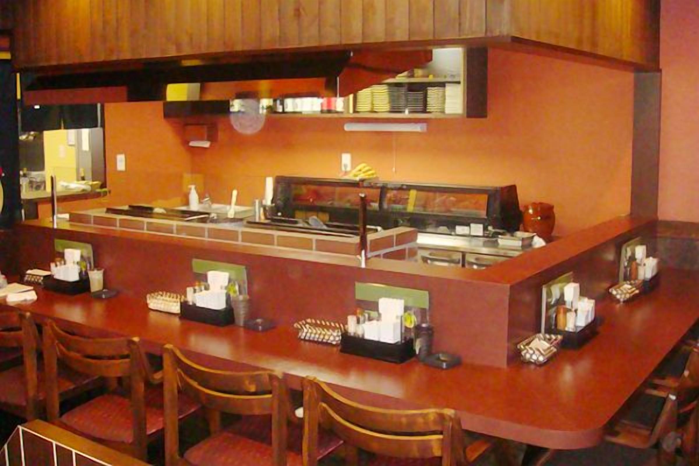 A restaurant with a bar area, multiple seating options, and a counter with food items.