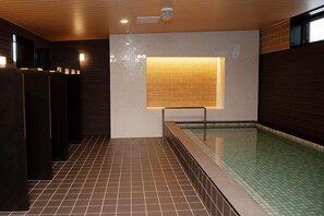 Zona de piscina con suelo de baldosas, lámpara empotrada en la pared y techo de madera.