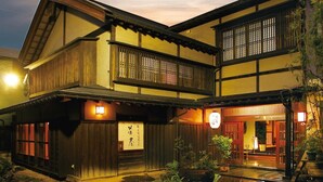Een traditioneel Japans gebouw met een houten gevel, een duidelijke ingang en een bord met Japanse tekens.