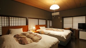 Een hotelkamer met twee bedden, een televisie en een plafondventilator.