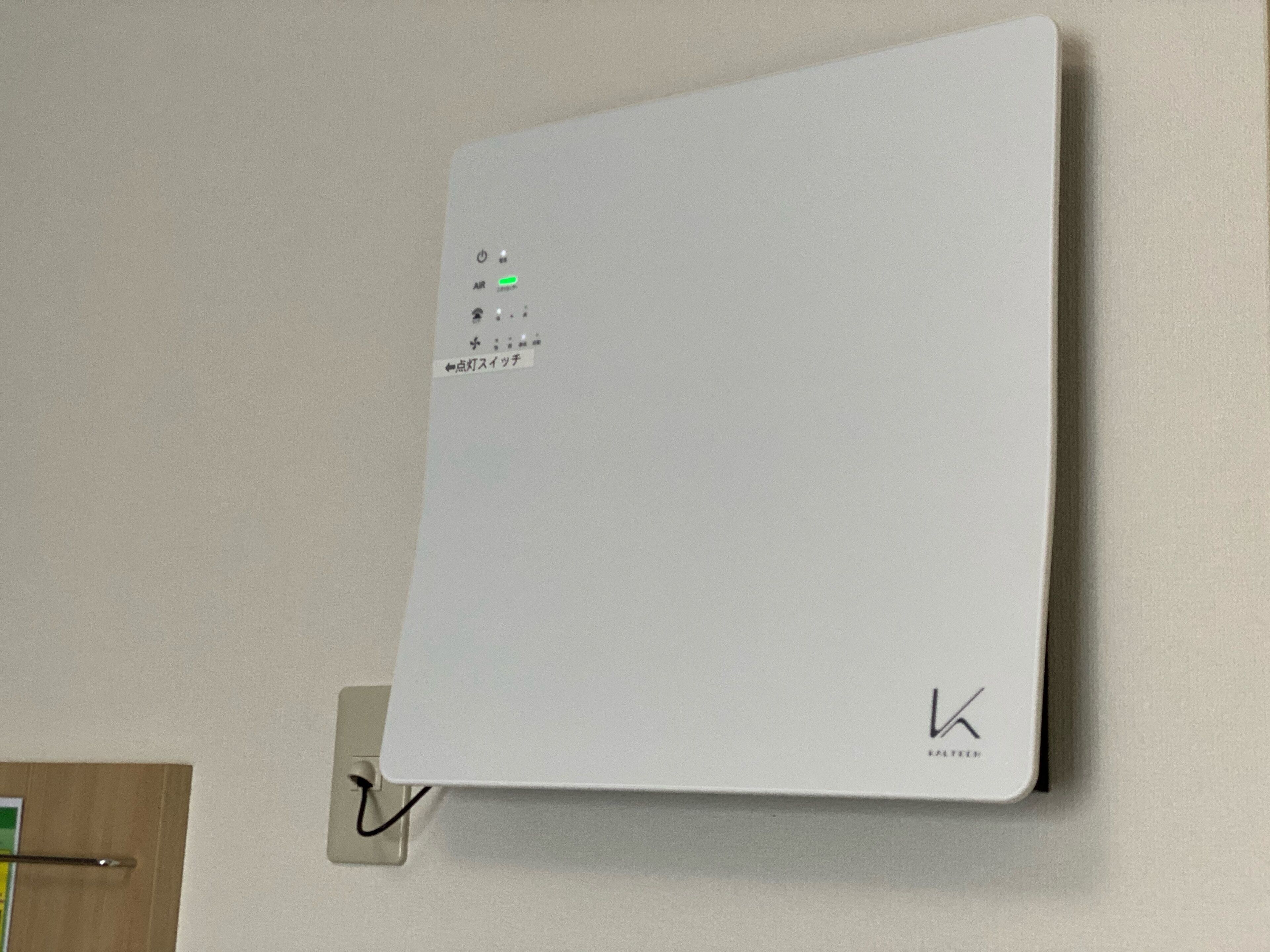 A white, wall-mounted thermostat with a digital display and control buttons.