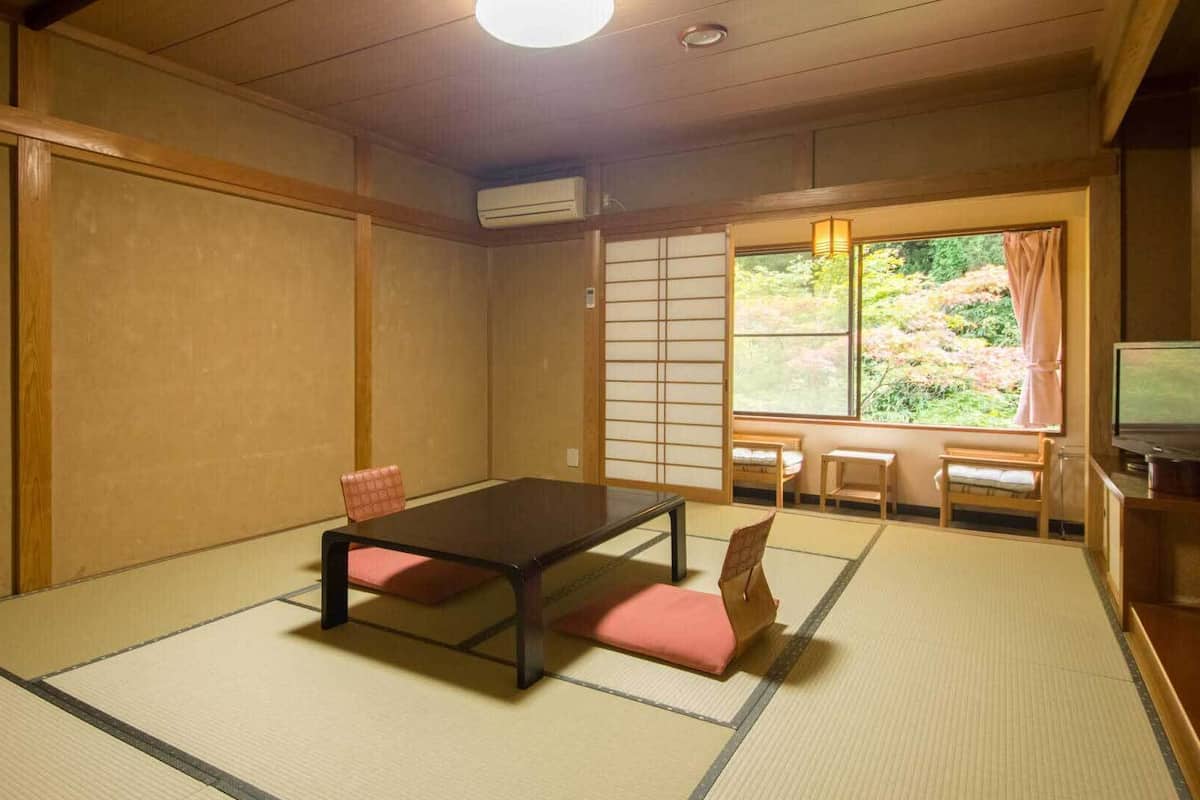 Una tradizionale stanza giapponese con pavimento in tatami, un tavolino basso e porte scorrevoli.