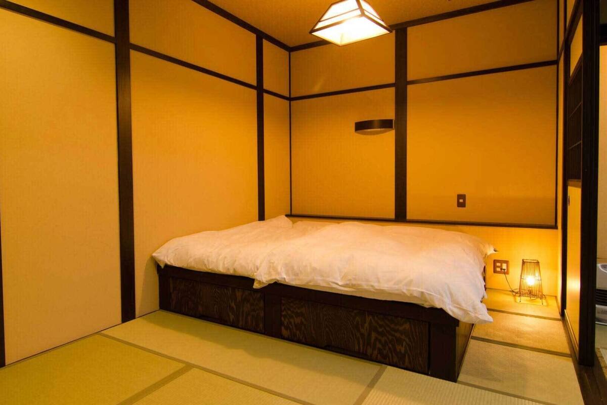 Una tradizionale stanza in stile giapponese con pavimento in tatami, un letto e una porta scorrevole shoji.