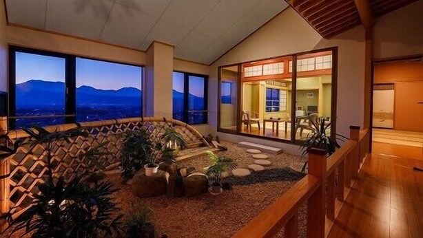 A spacious indoor area with a view of mountains, a wooden deck, and a seating area with plants.