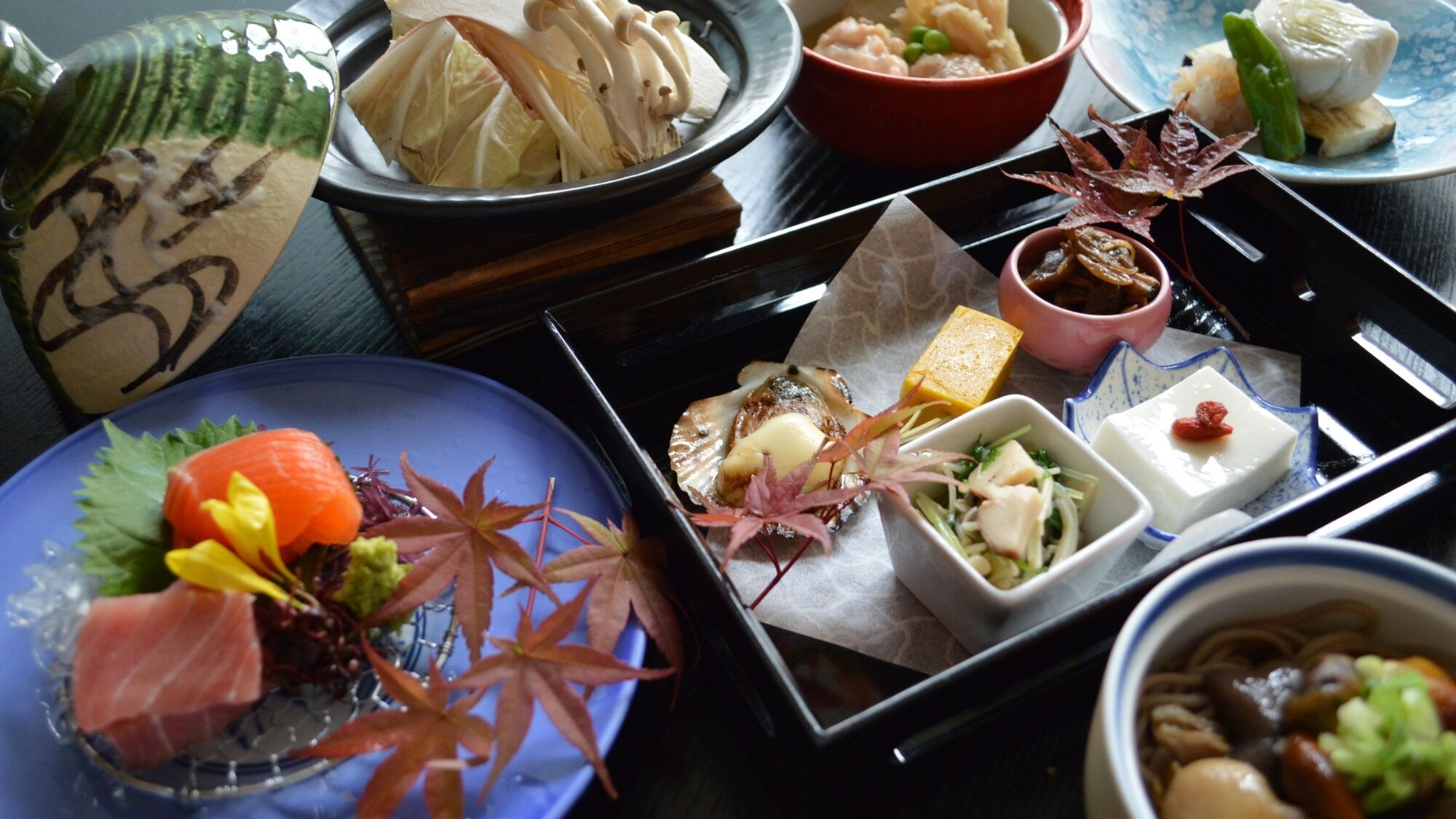 A variety of dishes and food items arranged on a tray, including sushi, sashimi, and other delicacies.