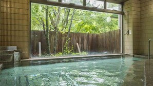 A hot tub with a view of trees through a large window. - Minakami Onsen Kkr Hotel Minakami Suimeiso (Minakami)