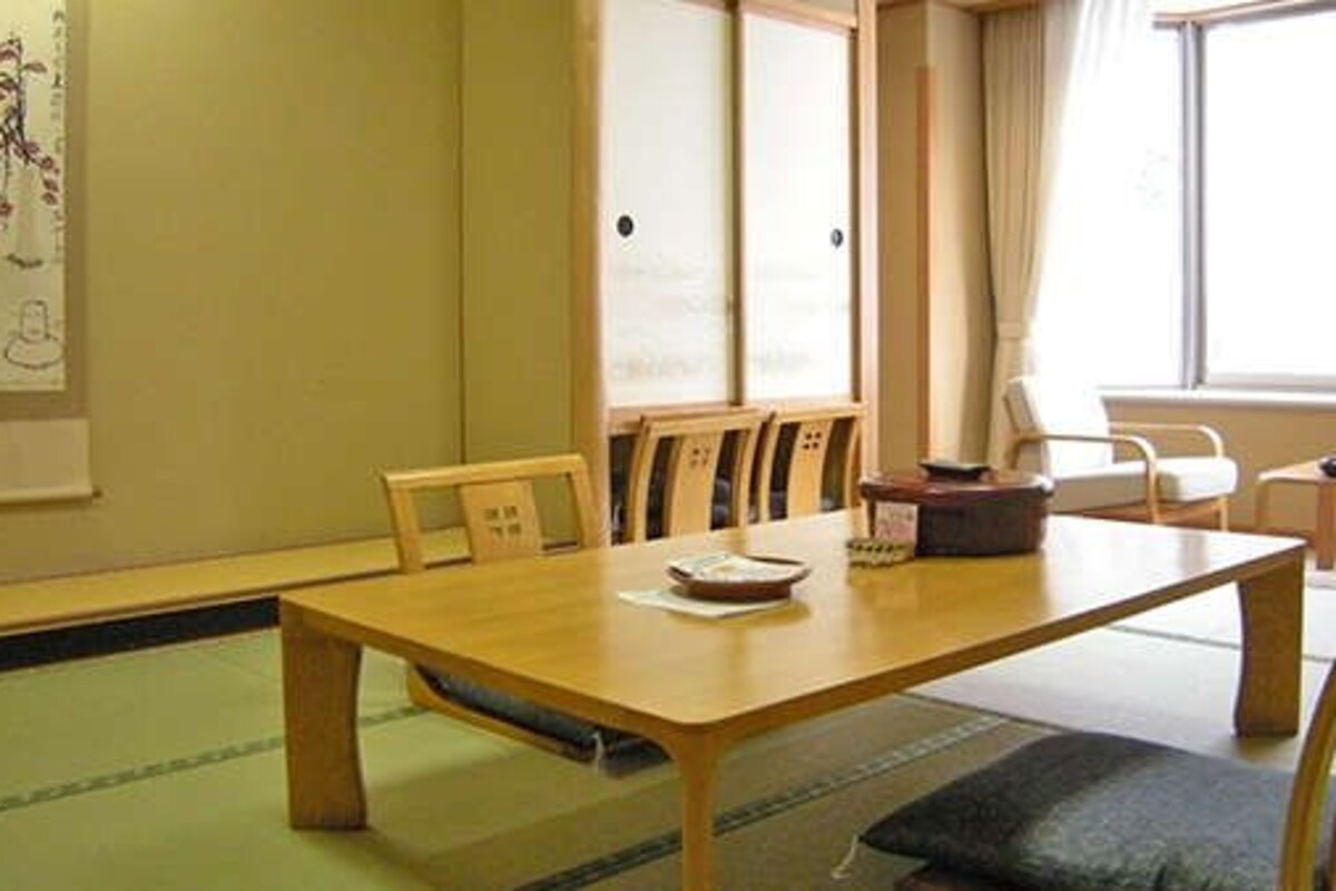A traditional Japanese-style room with tatami flooring, a low wooden table, and simple wooden chairs.