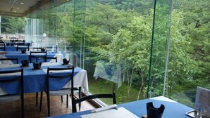 A restaurant with tables set for dining, a view of a forest through large glass windows, and a modern interior design. - Minakami Onsen Kkr Hotel Minakami Suimeiso (Minakami)