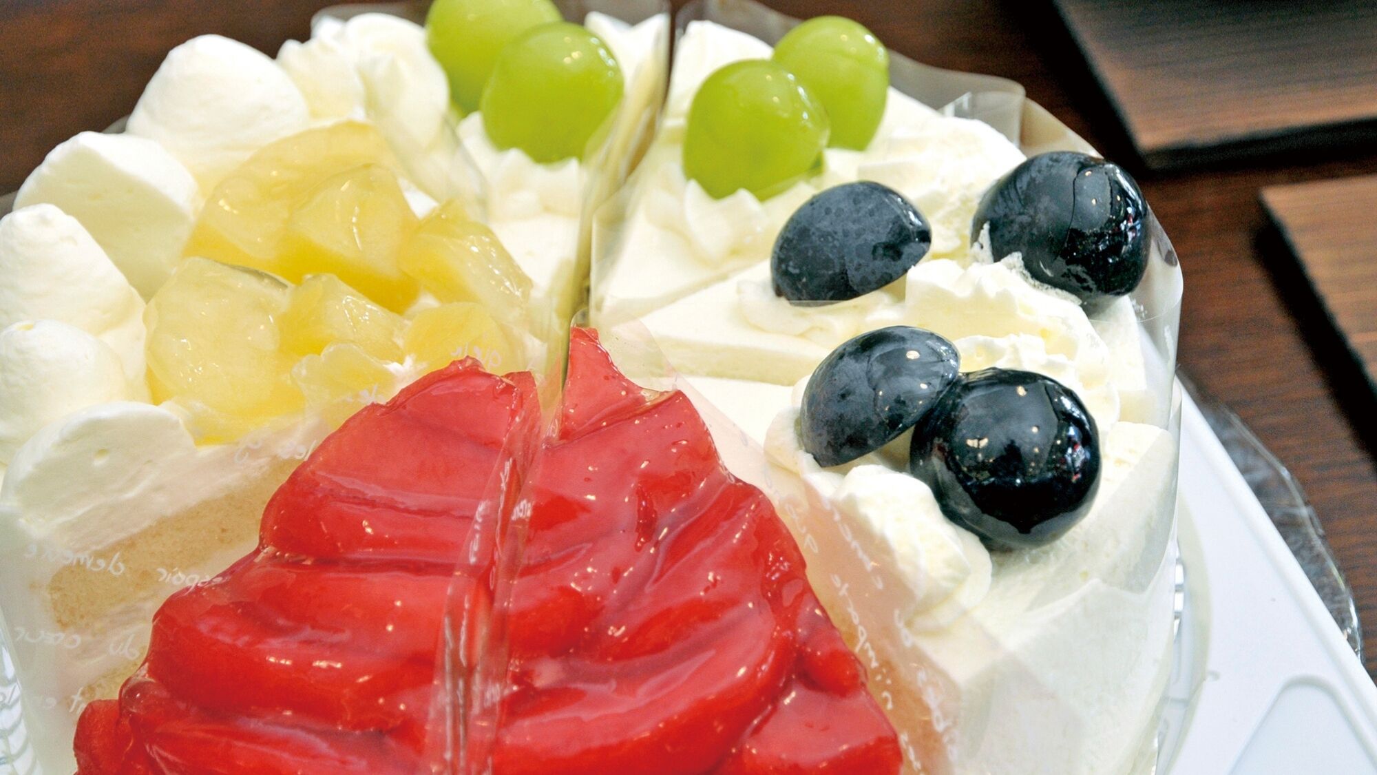 Un pastel con crema batida, fruta y un chorrito de jarabe rojo.
