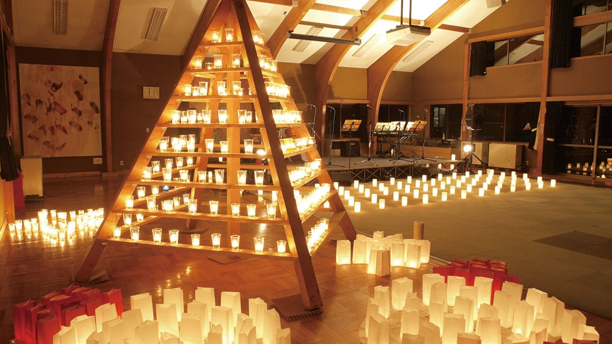 A large wooden structure with multiple tiers of candles, a stage with musical instruments, and a patterned wall in the background.