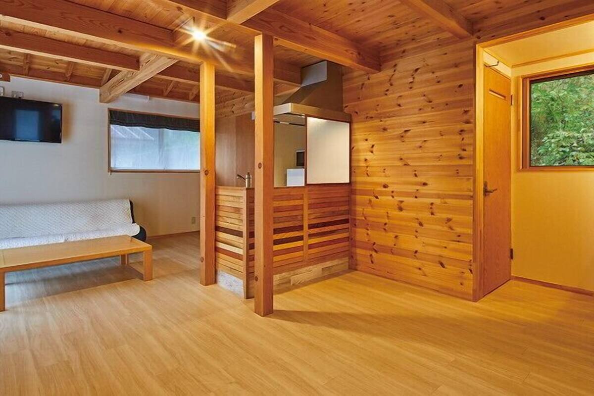 A wooden interior with a bench, a door, and a window.