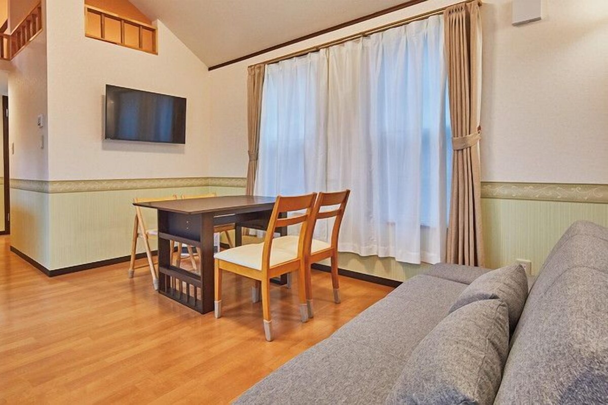 A compact living space with a dining area, a sofa, and a television.