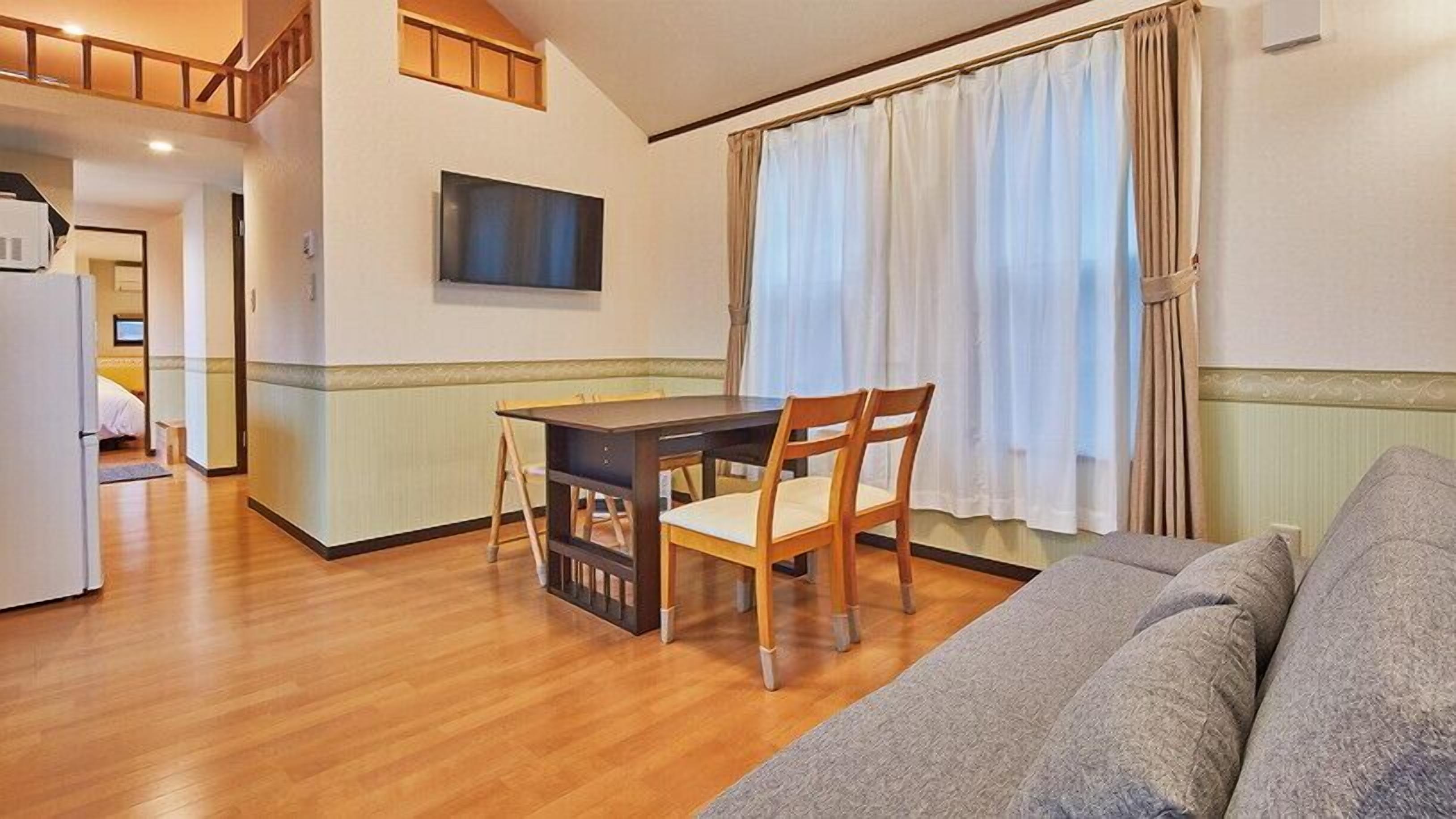 A compact living space with a dining area, a sofa, and a television.