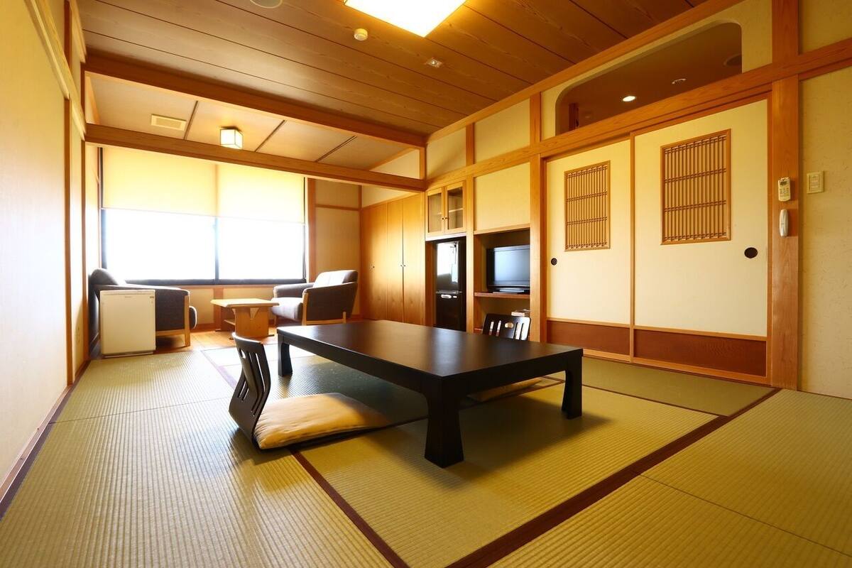 A traditional Japanese room with tatami flooring, a low table, a sofa, and sliding doors.