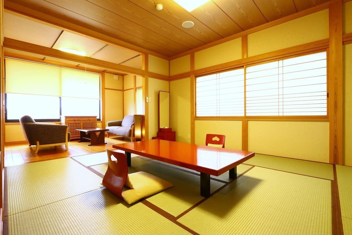 A traditional Japanese room with tatami flooring, a low table, a chair, and sliding doors.