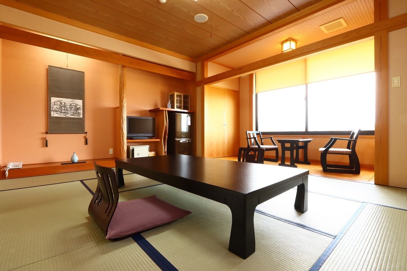 A traditional Japanese room with tatami flooring, a low table, and a television.