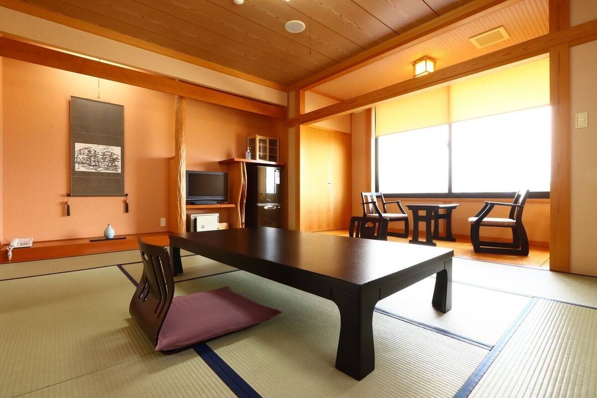 A traditional Japanese room with tatami flooring, a low table, and a television.