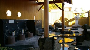 A traditional Japanese onsen with stone benches, a wooden structure, and a rock garden.