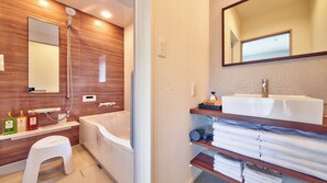 A modern bathroom with a bathtub, a vanity with a sink, and a mirror. - Green Park Santo (Maibara)