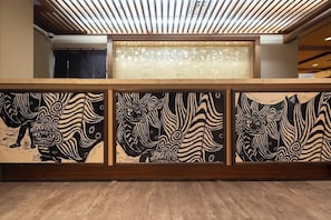 Un área de recepción con un mostrador de madera, paneles decorativos en la pared y un techo con listones.