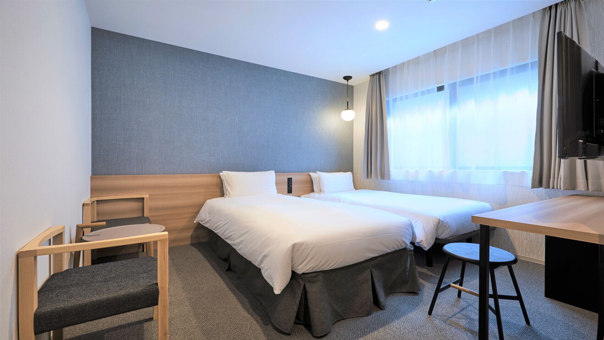 Ein Hotelzimmer mit Bett, Schreibtisch, Stuhl und Fernseher.