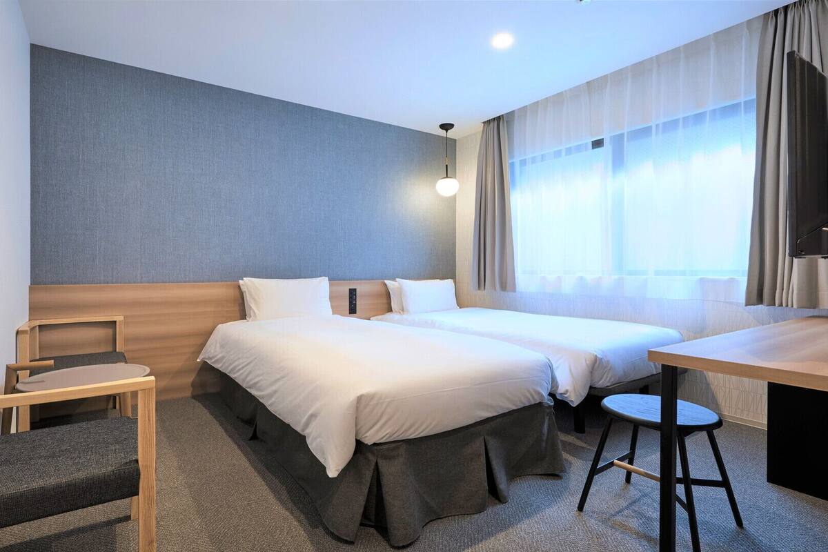 A hotel room with a bed, a desk, a chair, and a TV.