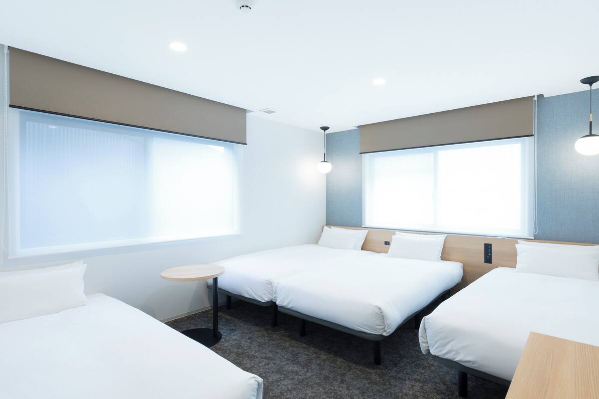 A hotel room with two single beds, a small round table, and a large window.