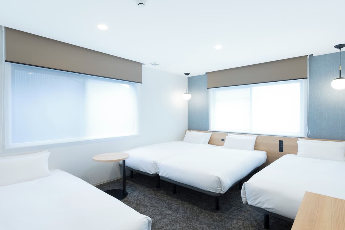 A hotel room with two single beds, a small round table, and a large window.