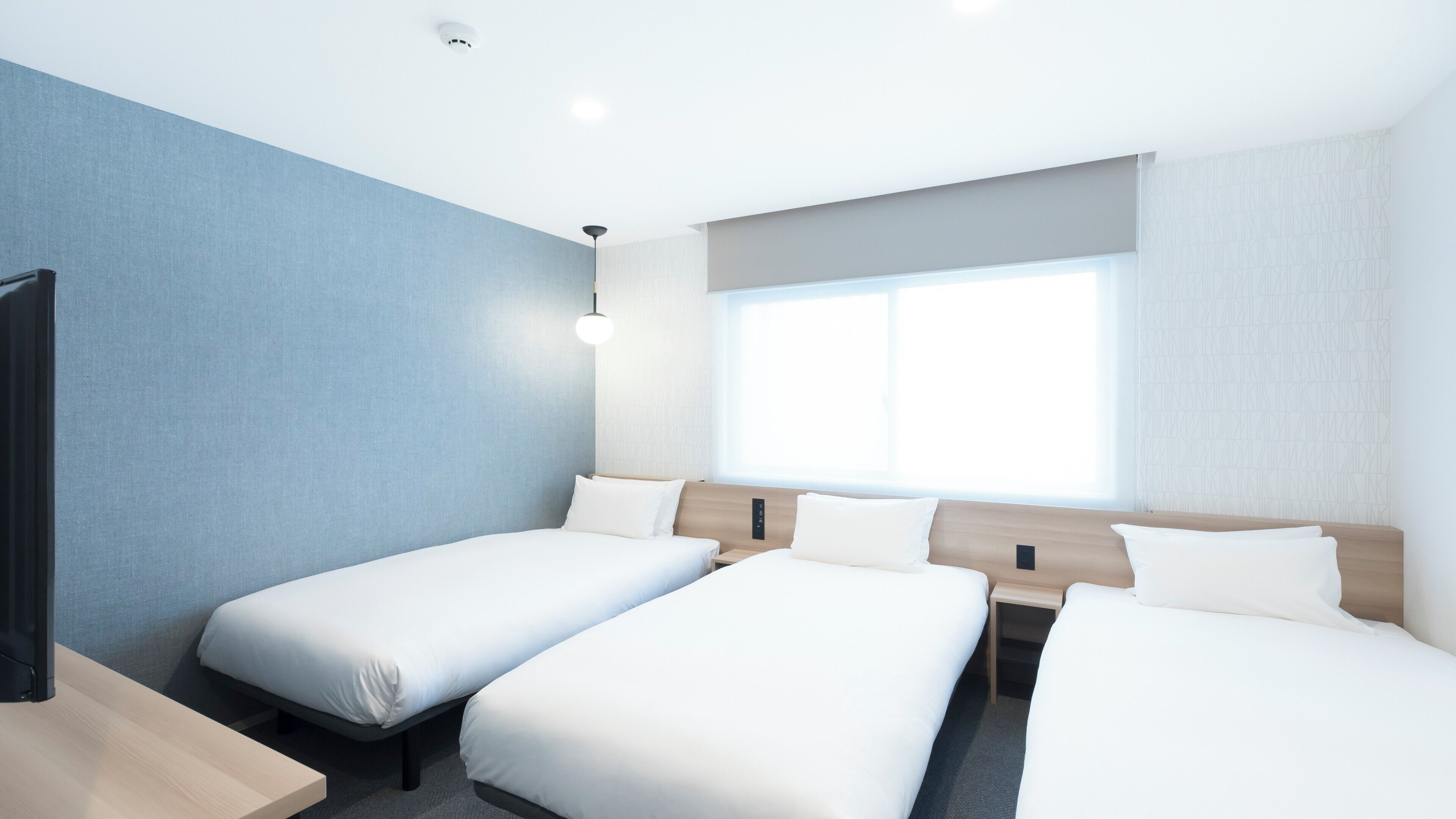 Ein Hotelzimmer mit zwei Einzelbetten, einem großen Fenster und einem modernen Design.