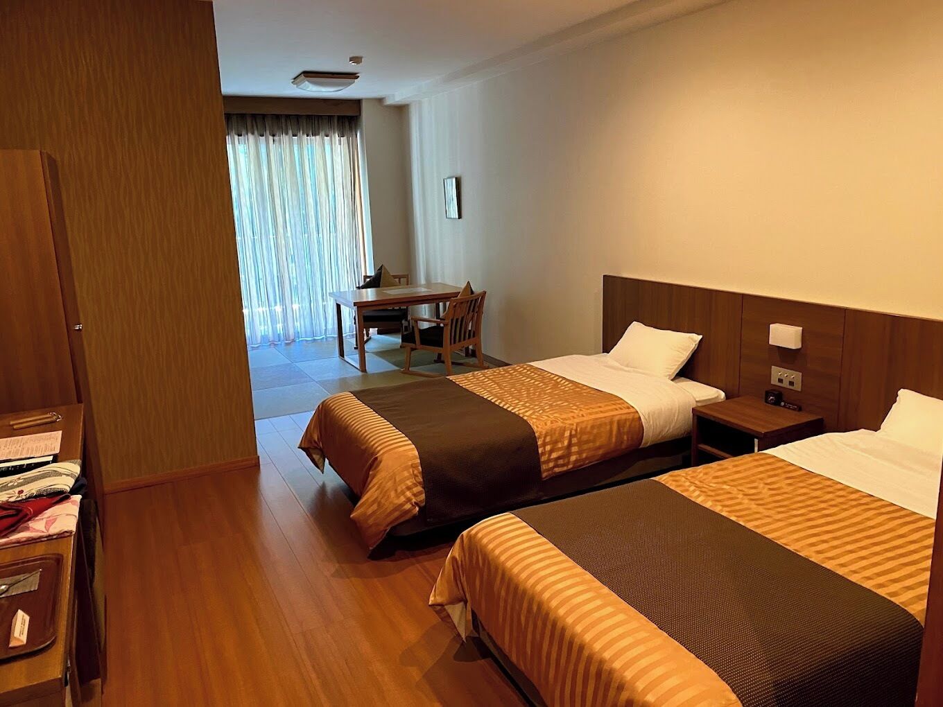 A hotel room with two beds, a desk, and a chair.
