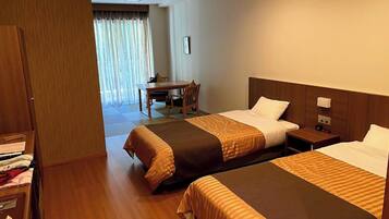 Quarto de hotel com duas camas, uma escrivaninha e uma cadeira.