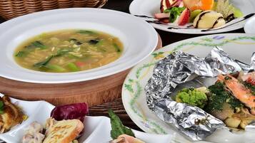 Verschiedene Speisen, darunter Suppe, Meeresfrüchte und Gemüse, auf einem Holztisch.