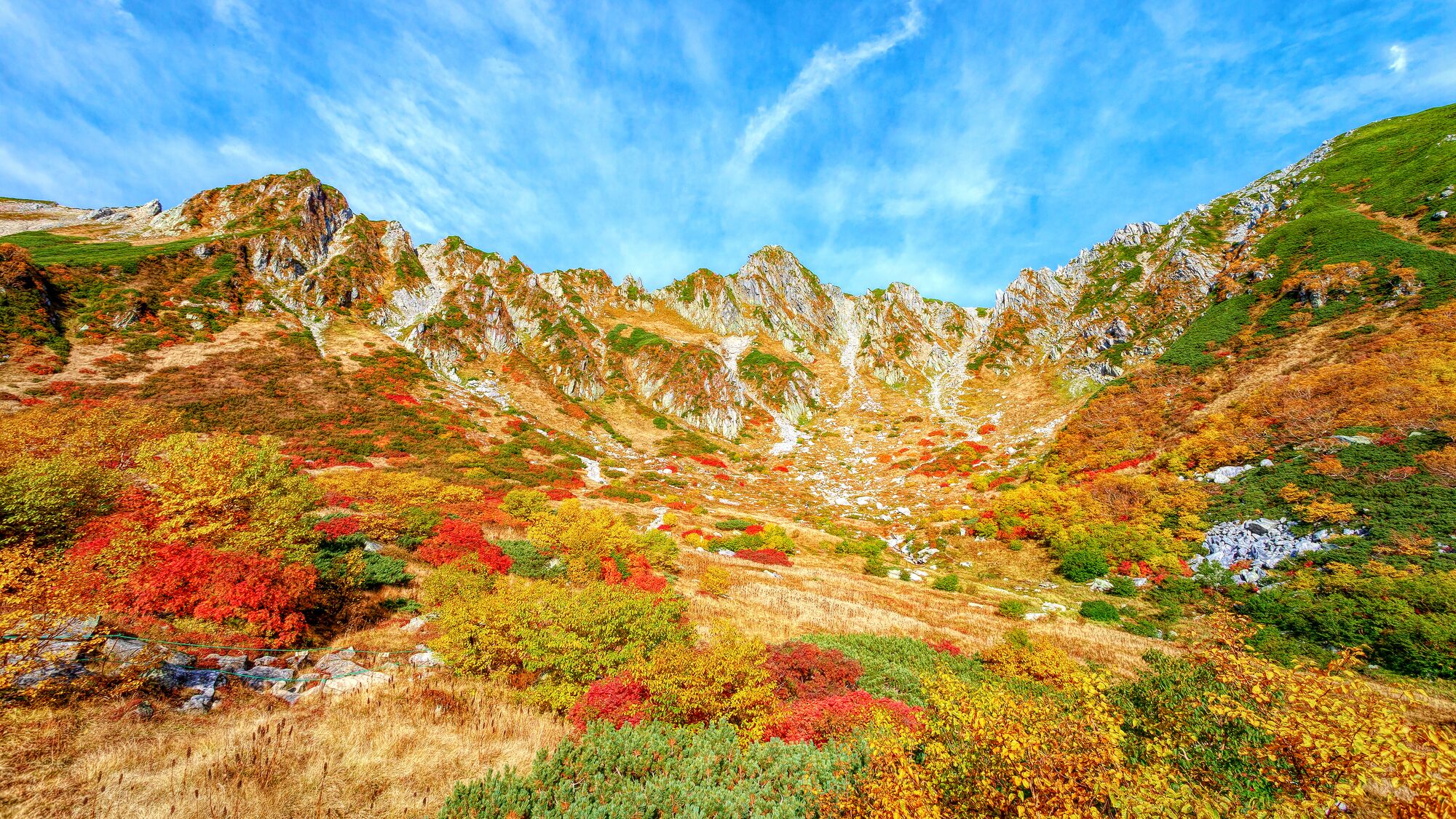 A mountainous landscape with a valley filled with colorful autumn foliage.