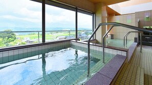 Una piscina con agua cristalina, una baranda metálica y vistas a un paisaje verde a través de amplias ventanas.