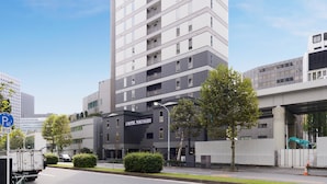 A modern hotel with a prominent 'J HOTEL TOKYOGEO' sign, a parking area, and a street view. - J Hotel Tokyo Geo (Tokyo)