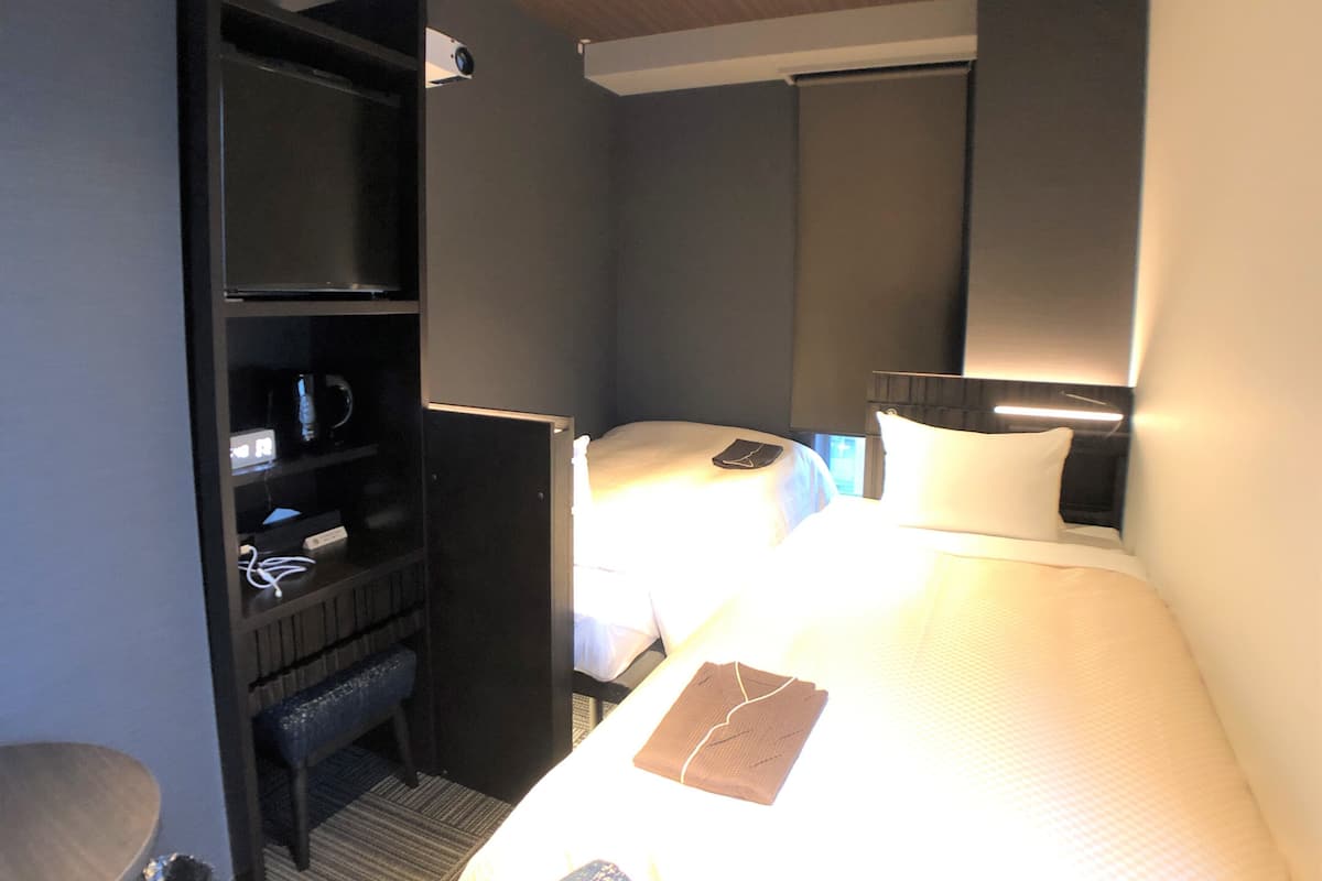 A hotel room with a bed, bedside table, and a built-in wardrobe.