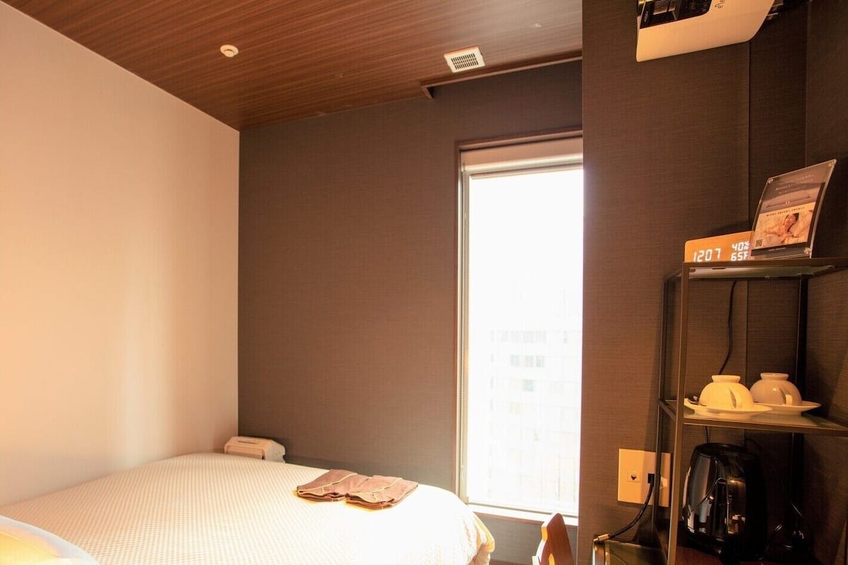 Ein Hotelzimmer mit Bett, Kaffeemaschine und Fenster.