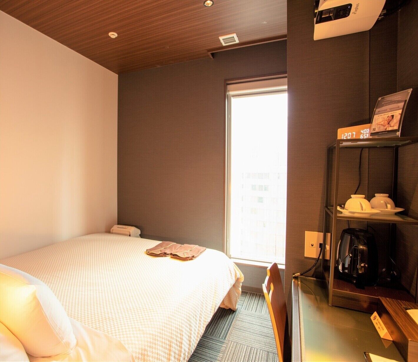 A hotel room with a bed, a coffee machine, and a window.