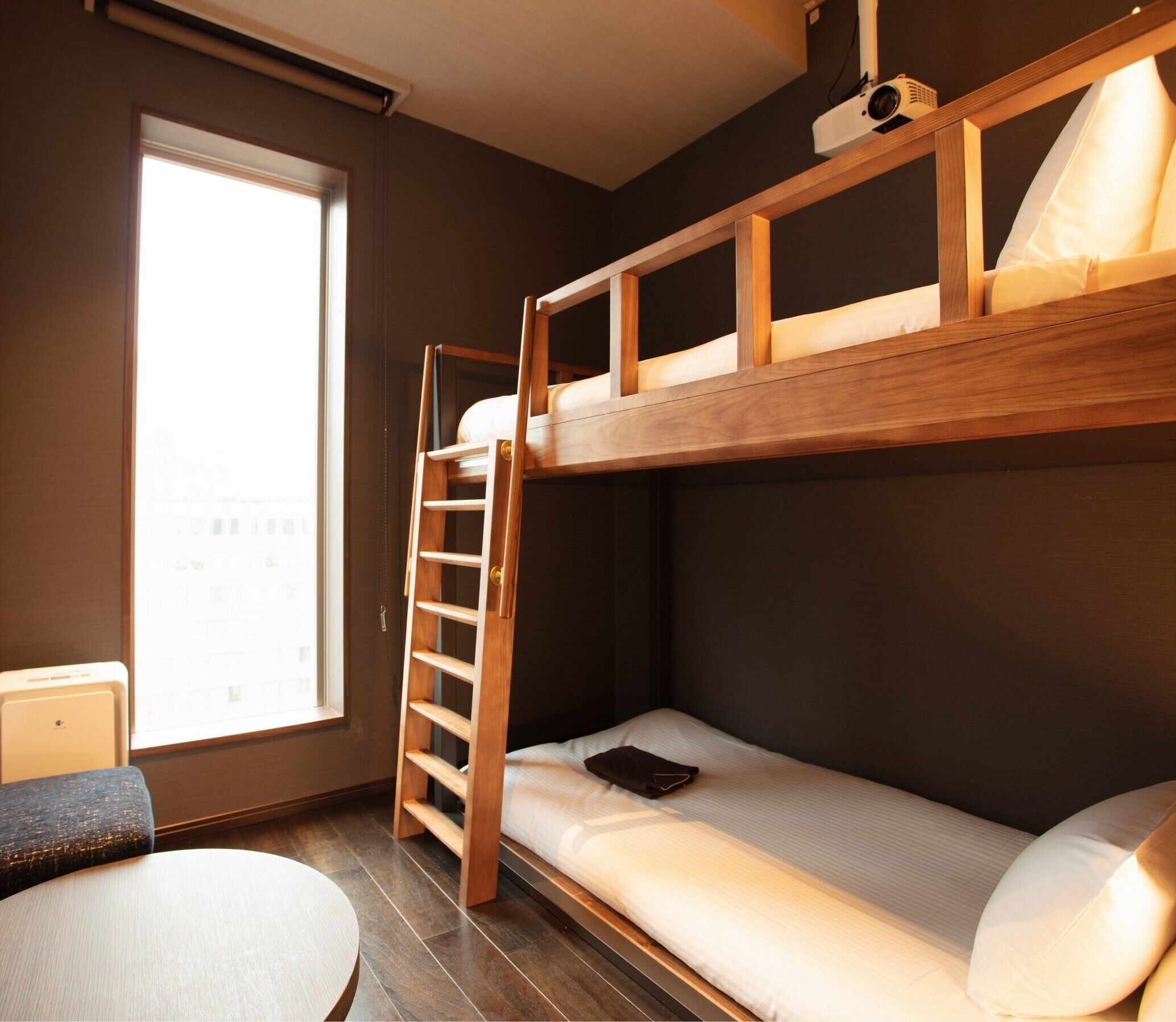 A bunk bed with a ladder, a small table, and a window with a view.