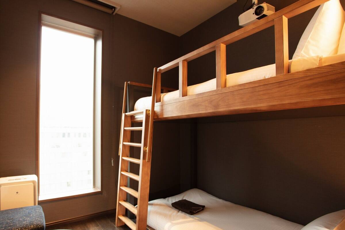 A bunk bed with a ladder, a small table, and a window with a view.