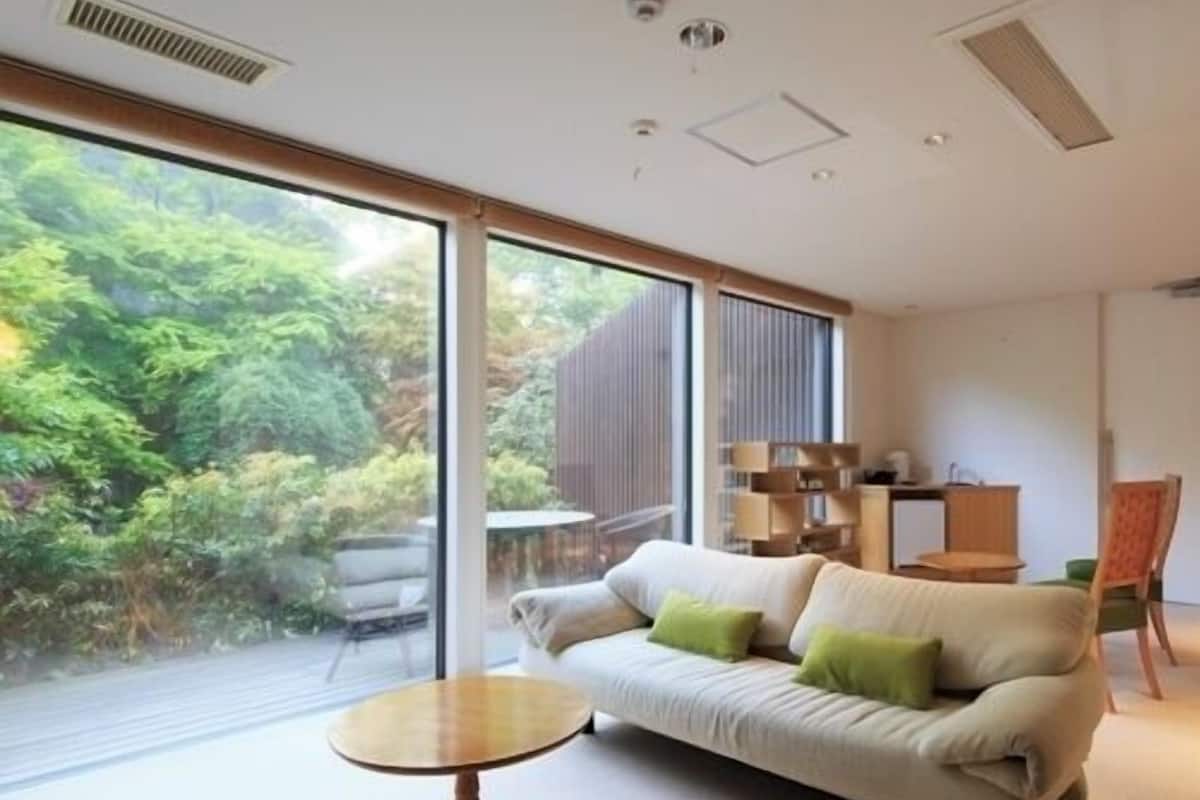 A modern living room with a sofa, a small round table, and a view of greenery outside.