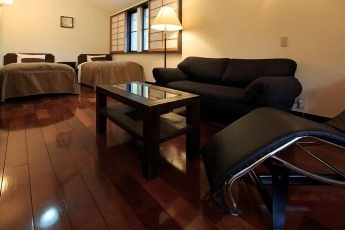 A room with a sofa, a table, and a lamp.
