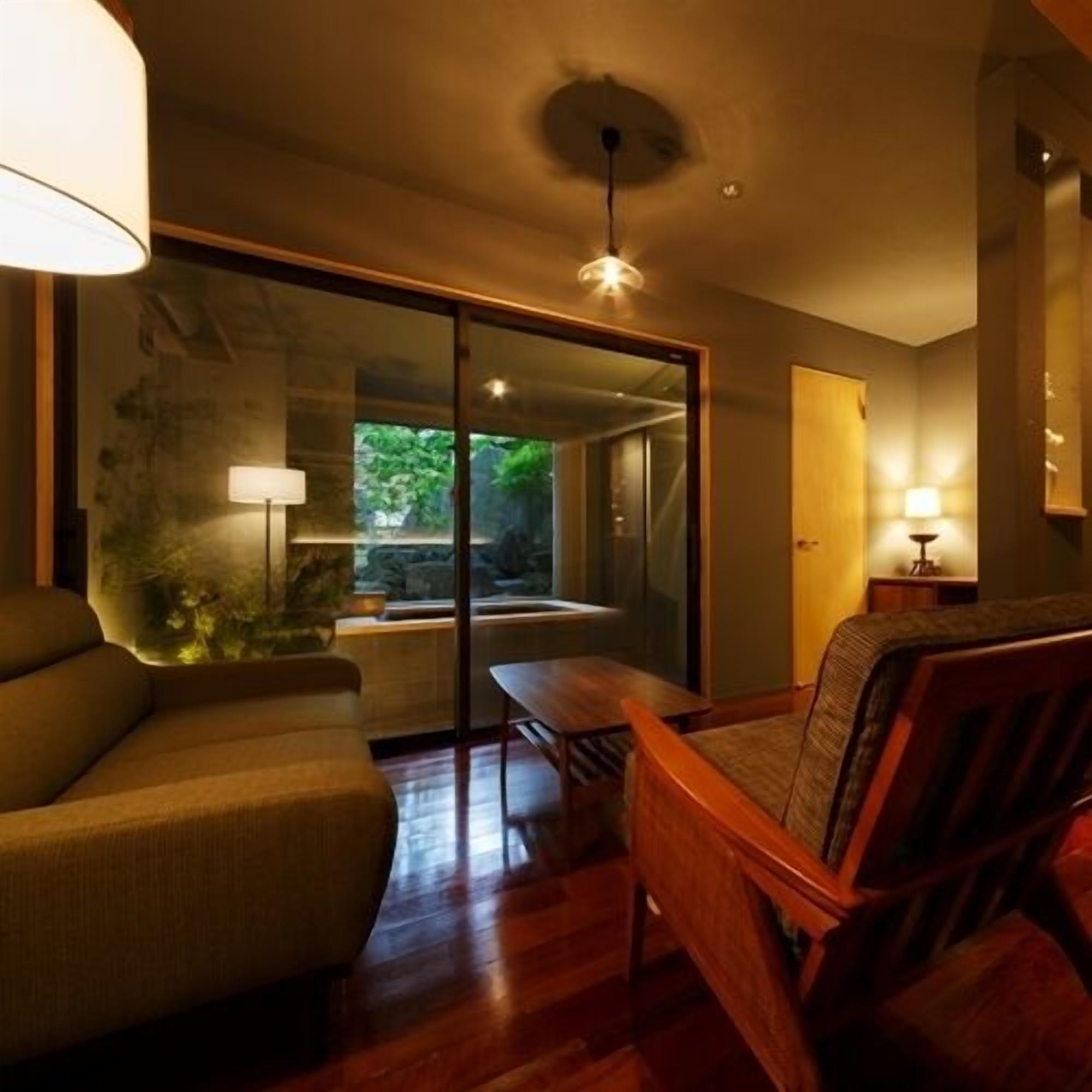 Un interior moderno con un sofá, una mesa de madera y un ventanal de vidrio que da a un jardín.